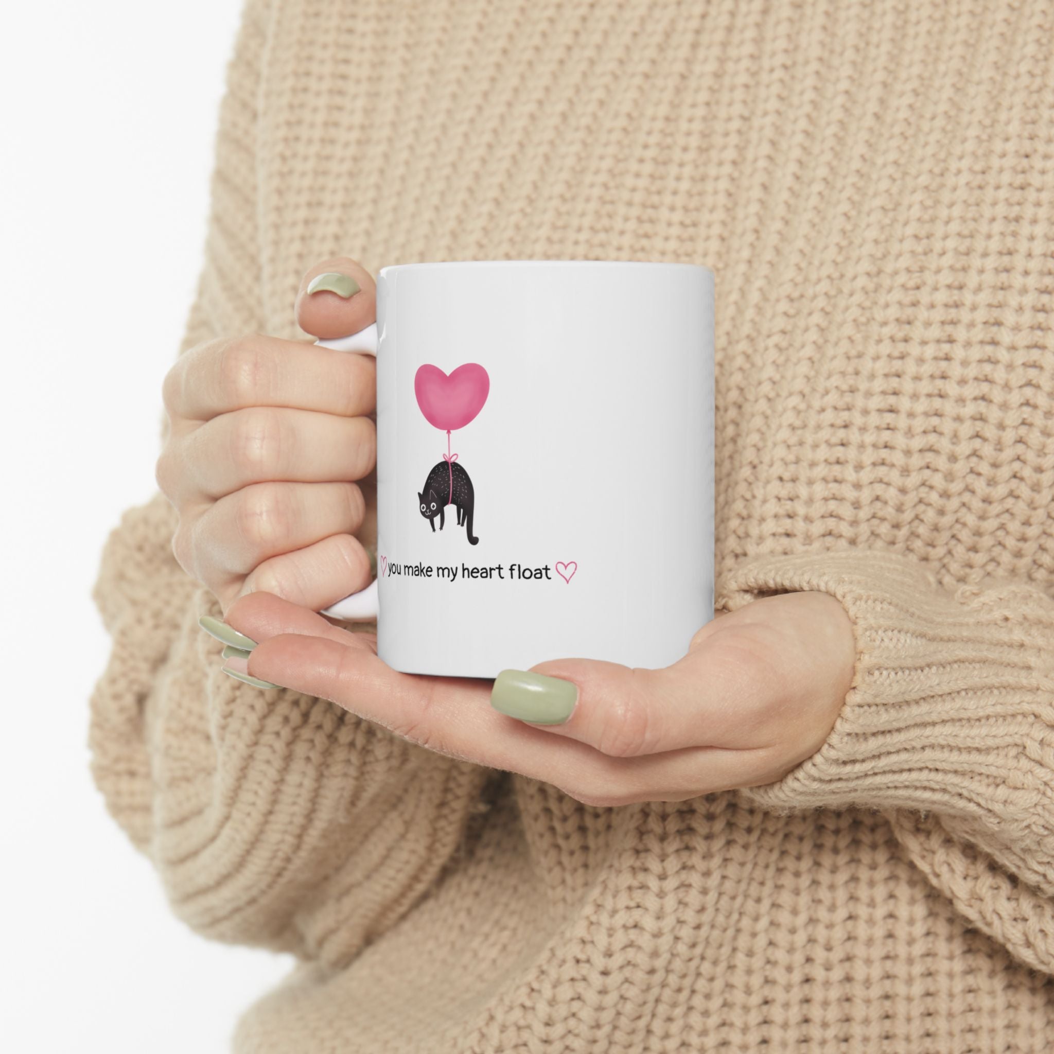 Woman holding cat mug that says "you make my heart float"