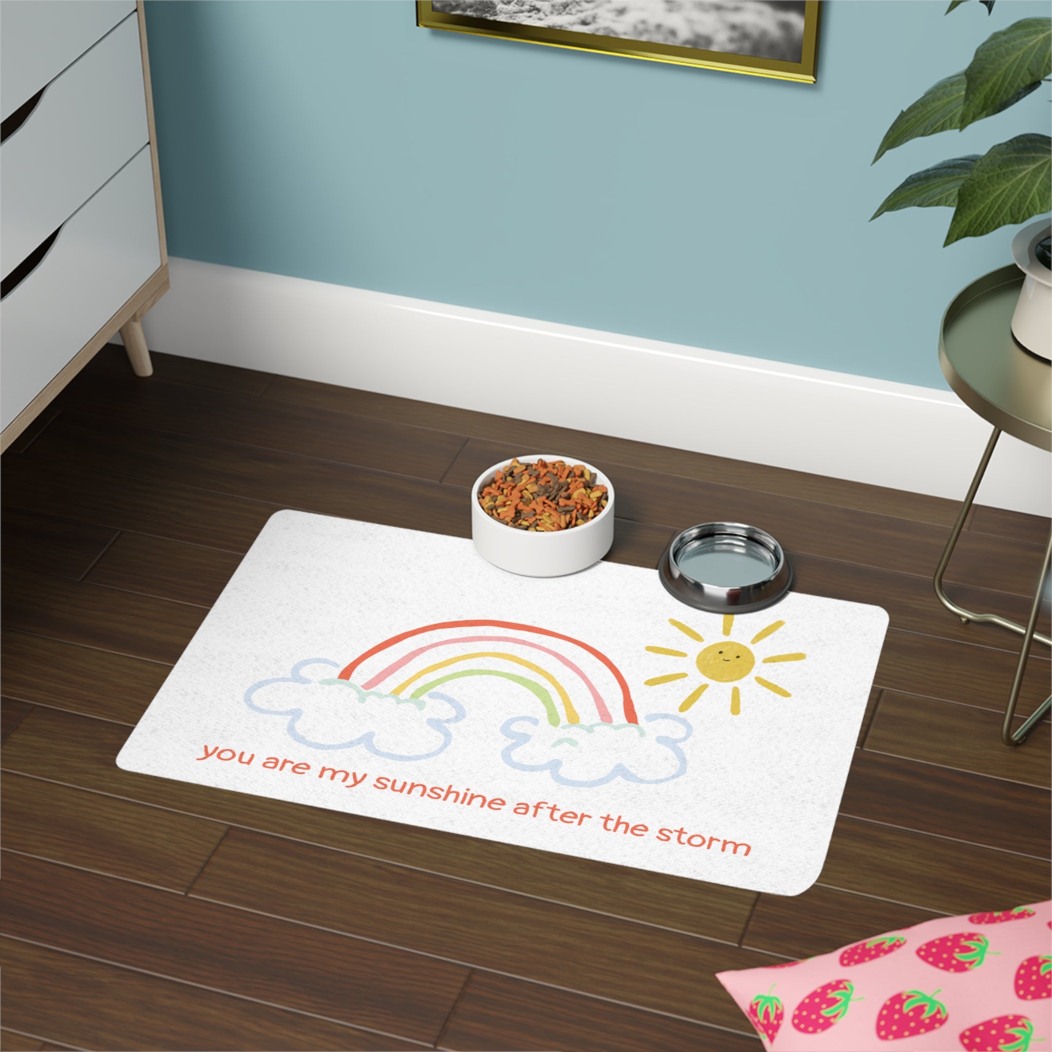 White mat with phrase "you are my sunshine after the storm" on a wooden floor, next to a bowl and water dish.