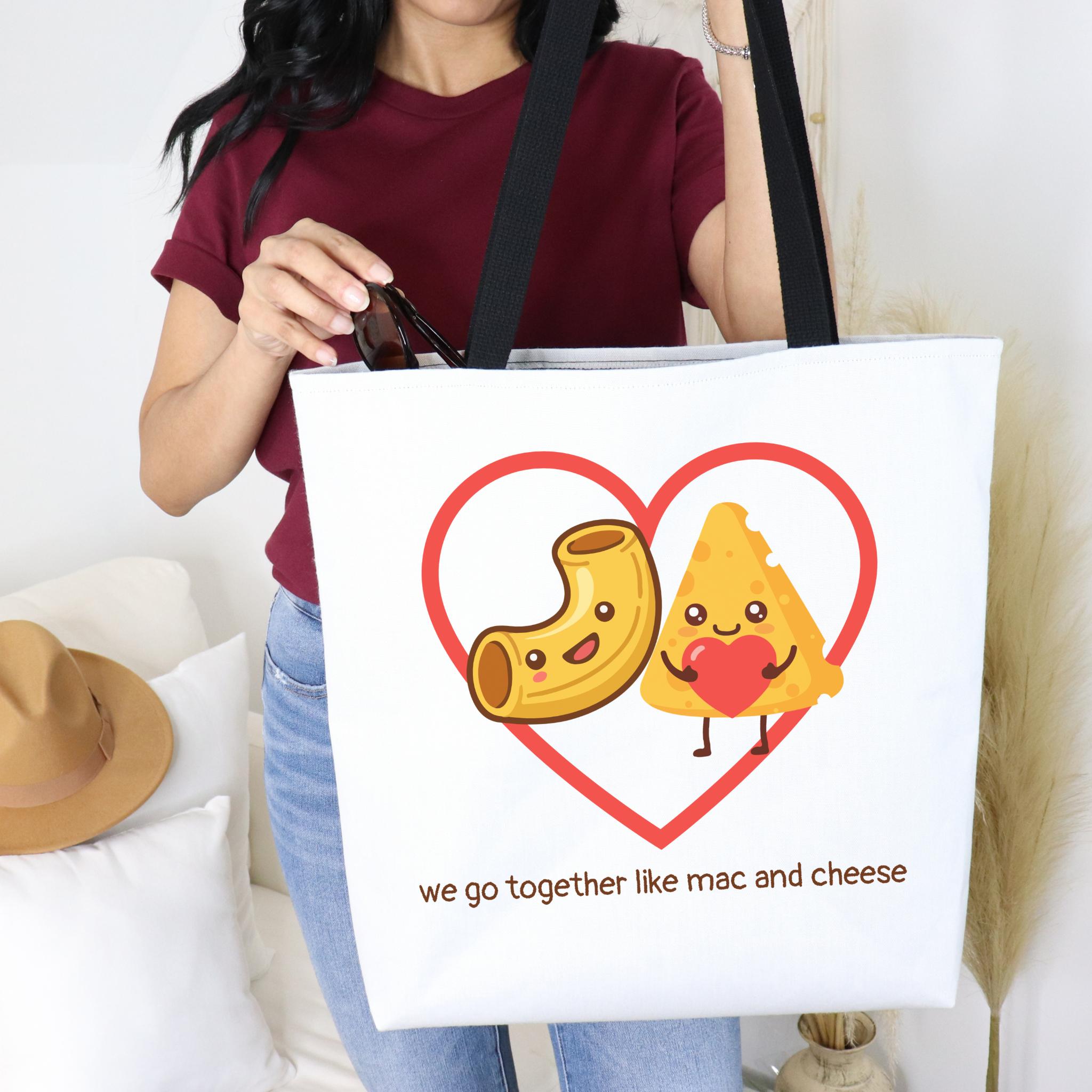 Person holding a tote bag with mac and cheese design that says "we go together like mac and cheese"