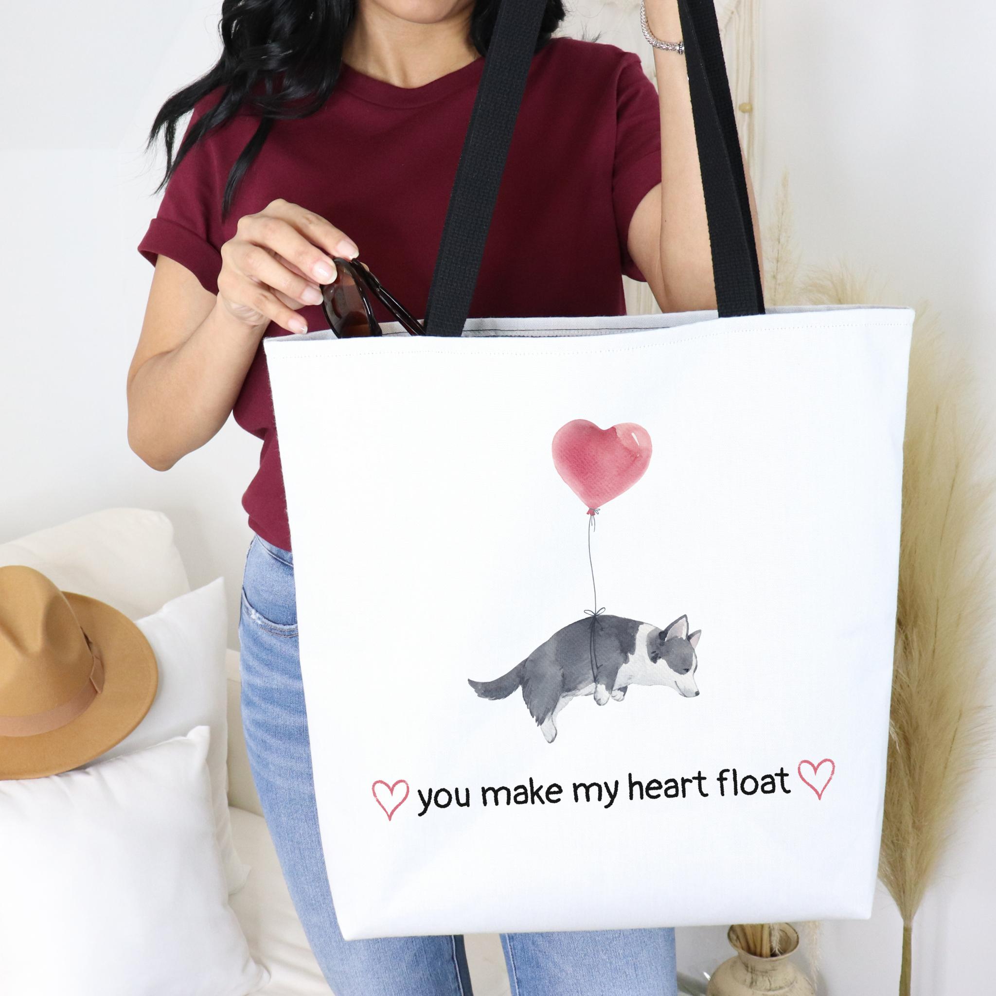 Person holding a tote bag with a dog and heart design and text.