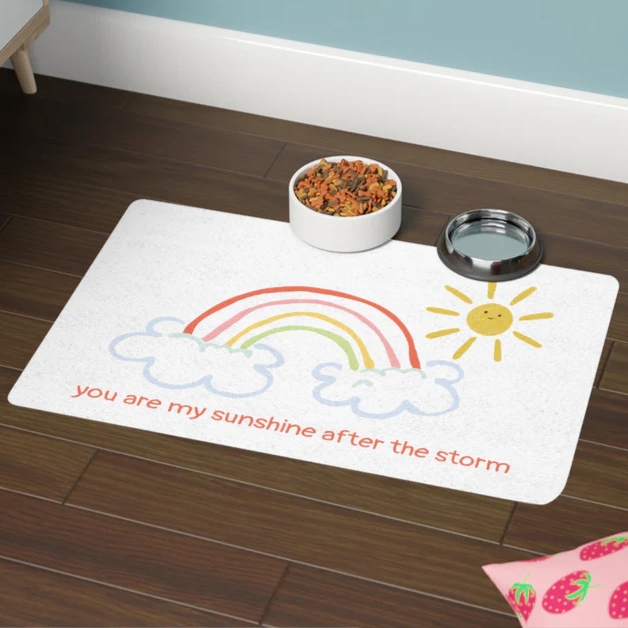 Pet mat with rainbow and sun design on a wooden floor
