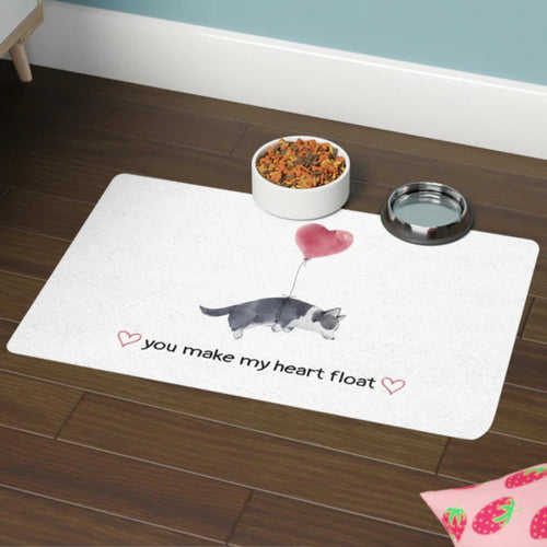 Pet mat with a dog and heart illustration and text on a wooden floor.